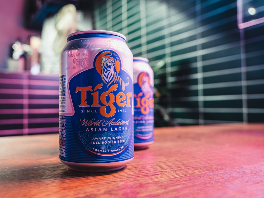 duas latas de cerveja tigre sentadas em uma mesa