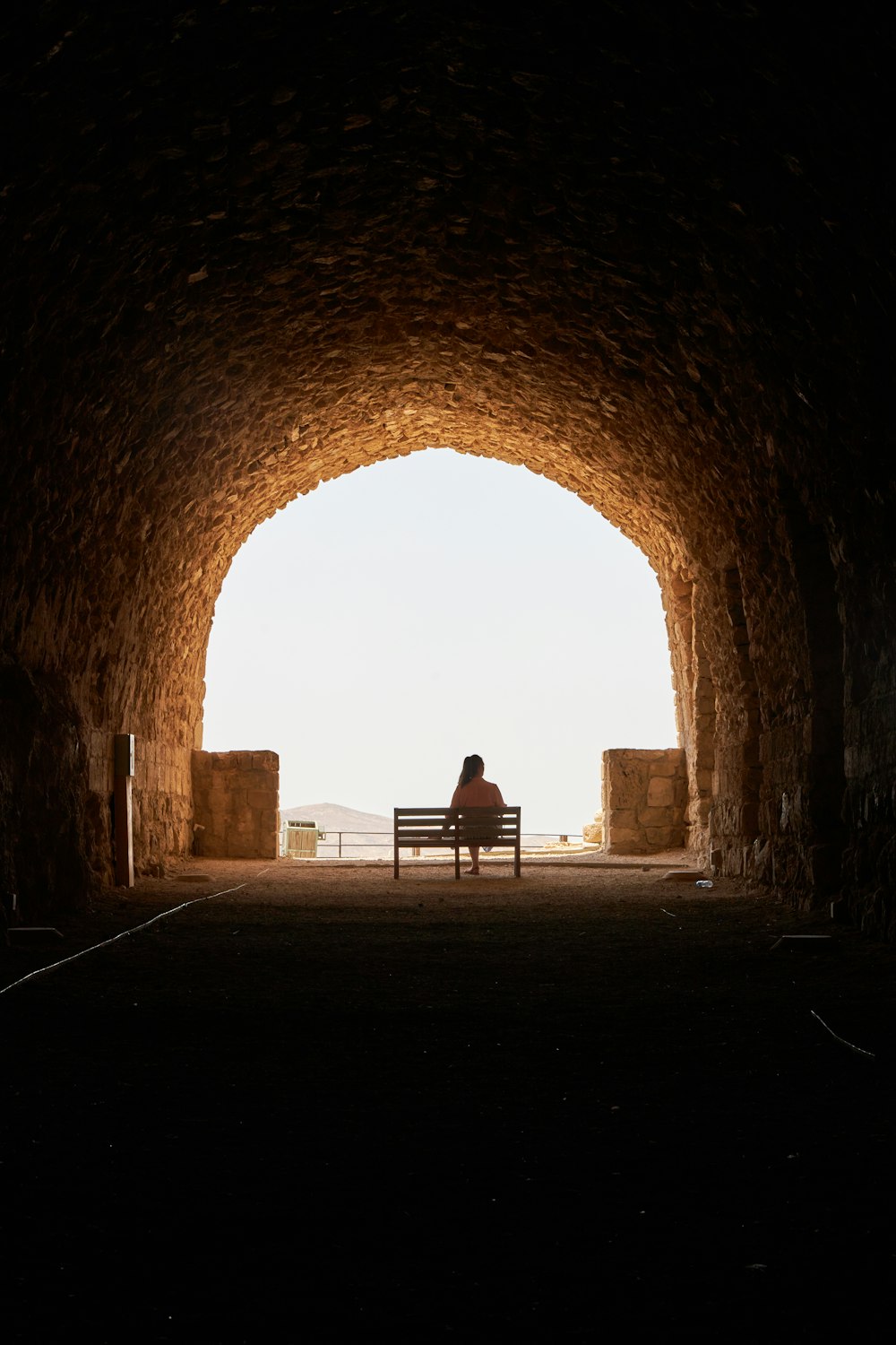 a person sitting on a bench in a tunnel