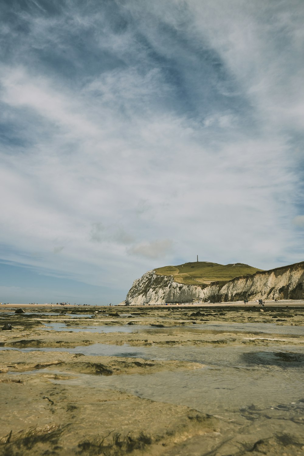 a sandy beach with a hill in the background