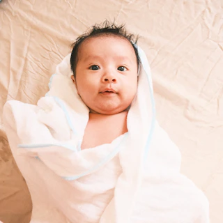 a baby wrapped in a blanket on top of a bed