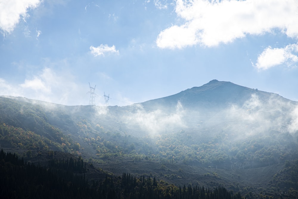 a mountain covered in fog and clouds with a radio tower in the distance