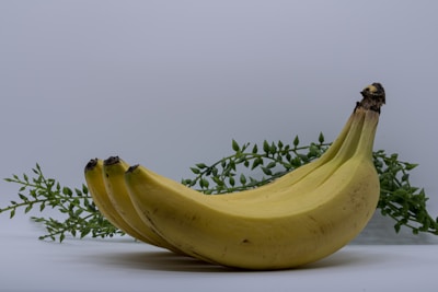 Artisan hand arranging banana chips in a small basket with green leaves around.