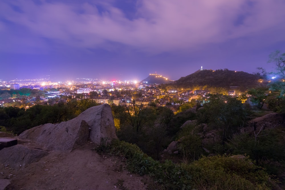 Blick auf eine Stadt bei Nacht von einem Hügel aus