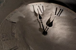 An ultra-realistic close-up of an ancient clock with shadows creeping over its face.
