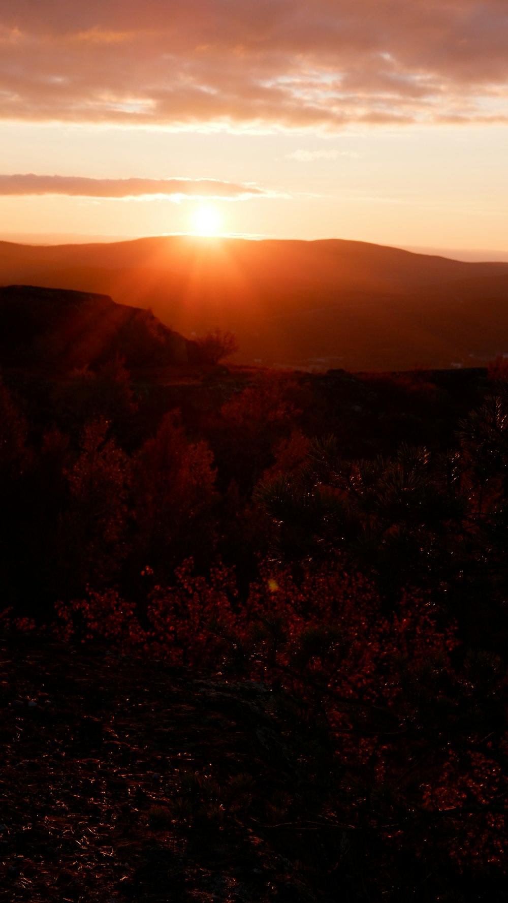 the sun is setting over the hills and trees