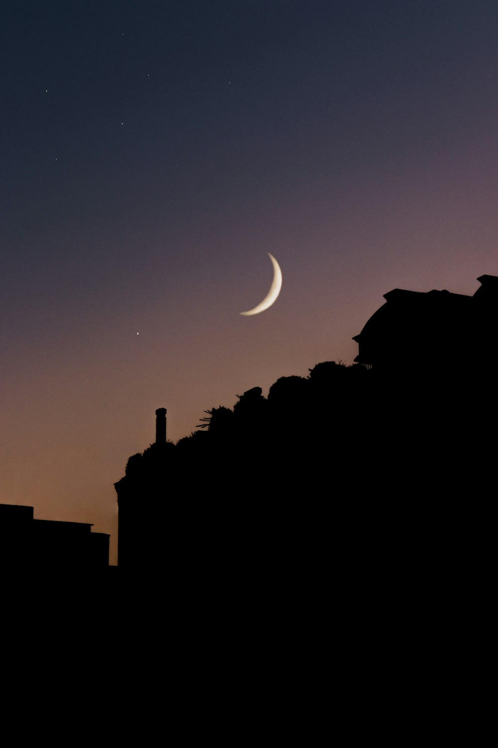 a crescent is seen in the night sky