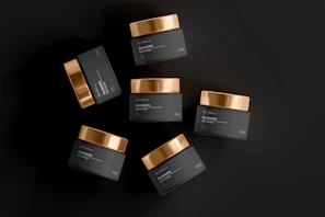 Artistic shot of premium hair wax containers arranged on a dark surface with dramatic lighting.