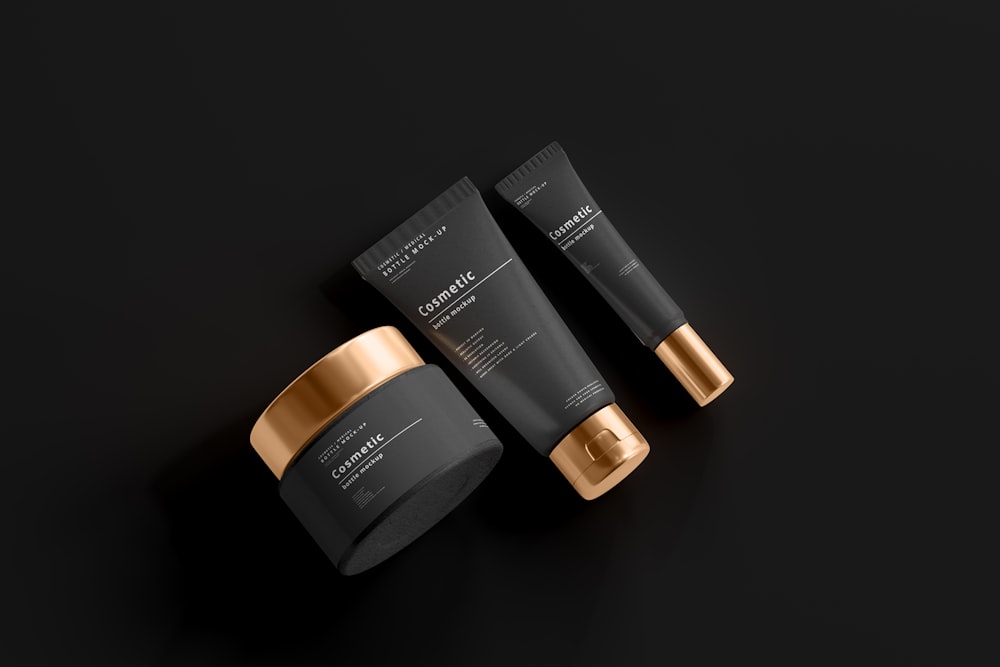 two black and gold tube containers on a black surface