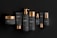 A collection of black and gold cosmetic containers arranged in a row. The set includes a jar, tubes, bottles with pumps, and a dropper bottle. Each item is designed with a matte black finish and shiny gold accents, giving a luxurious and elegant appearance. The products are labeled with the word 'cosmetic' and have simple, minimalistic typography.