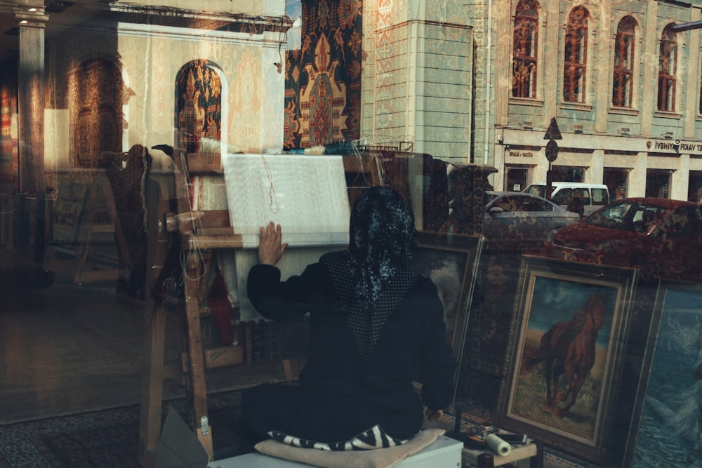 a woman sitting on a chair in front of a painting