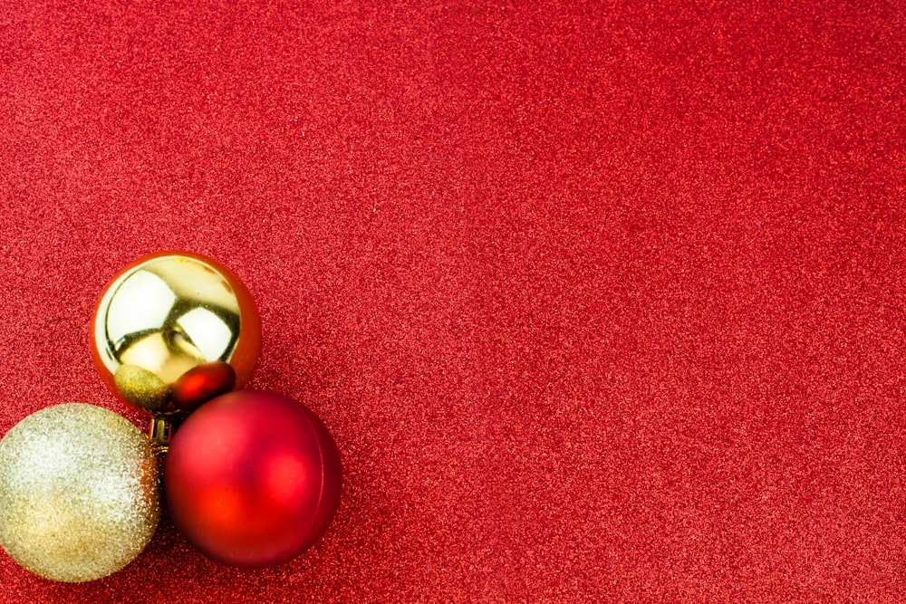 two shiny red and gold ornaments on a red background