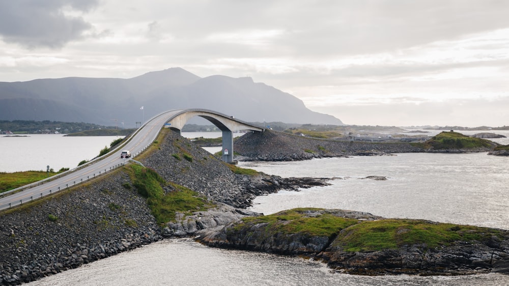 a bridge over a body of water with mountains in the background