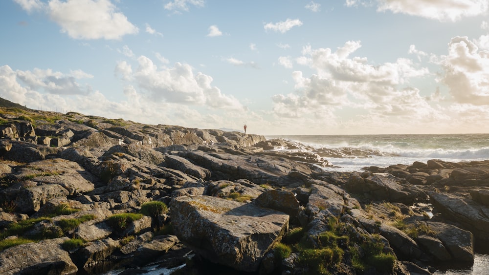 une personne debout sur une plage rocheuse au bord de l’océan