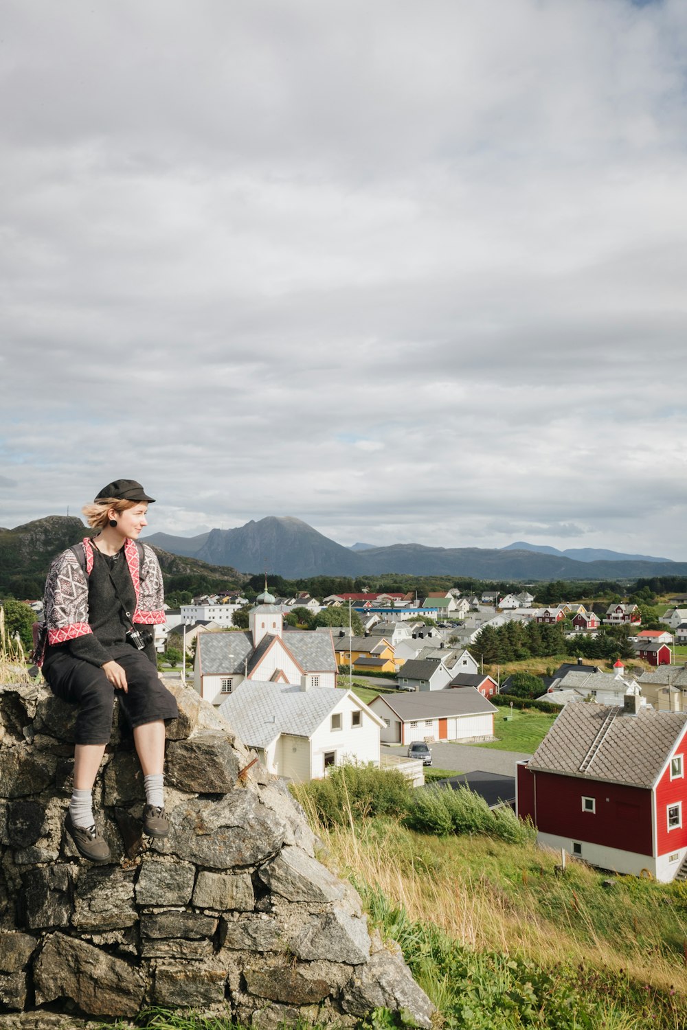 a woman sitting on top of a stone wall