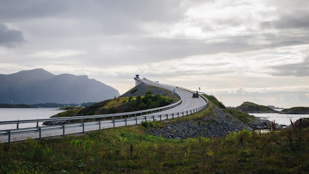 a car driving down a road next to a body of water