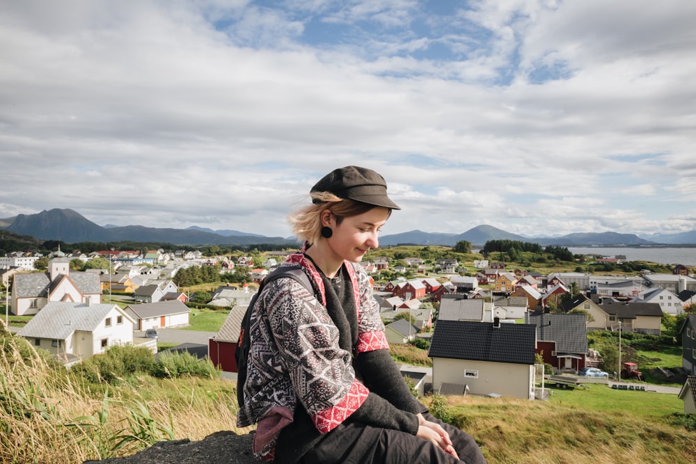 a woman sitting on top of a hill next to a town