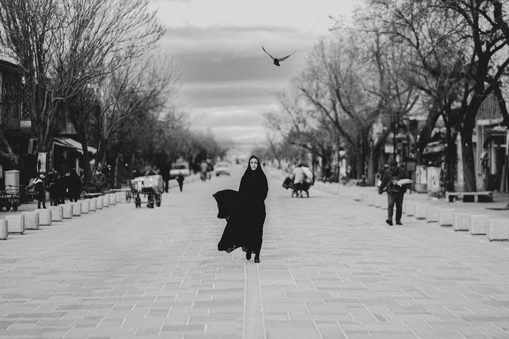 a woman walking down a street in a black and white photo