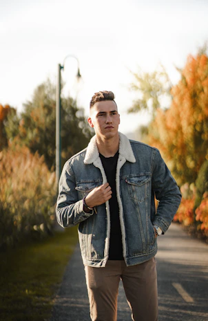 A model strolling through a leafy park wearing a durable, relaxed-fit jacket in warm autumn colors.