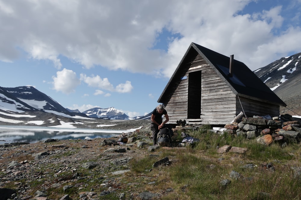 a man standing in front of a wooden cabin