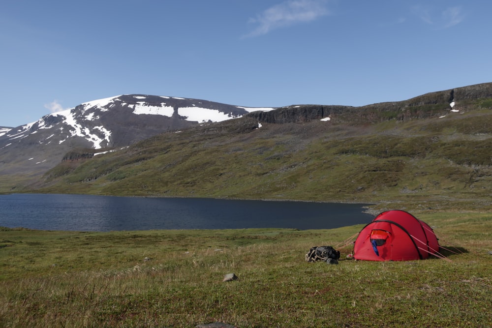 a red tent sitting on top of a lush green field