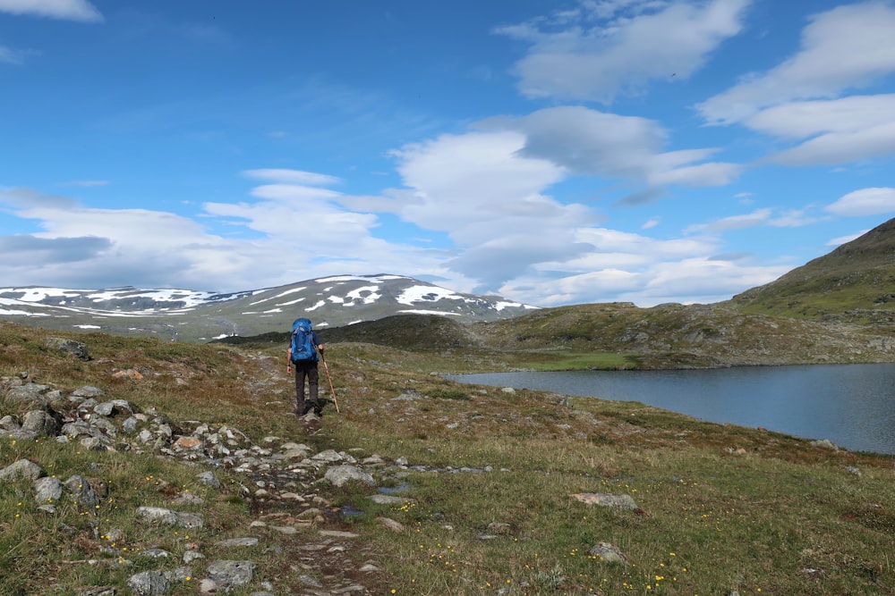 a man hiking up a hill near a lake