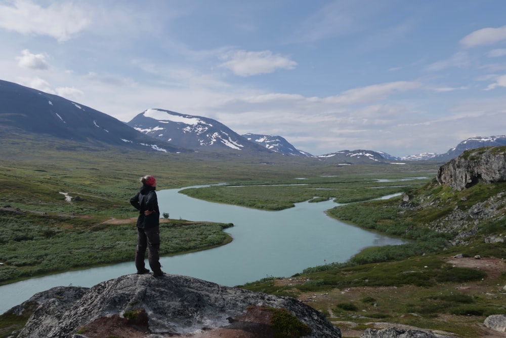 a man standing on top of a rock next to a river