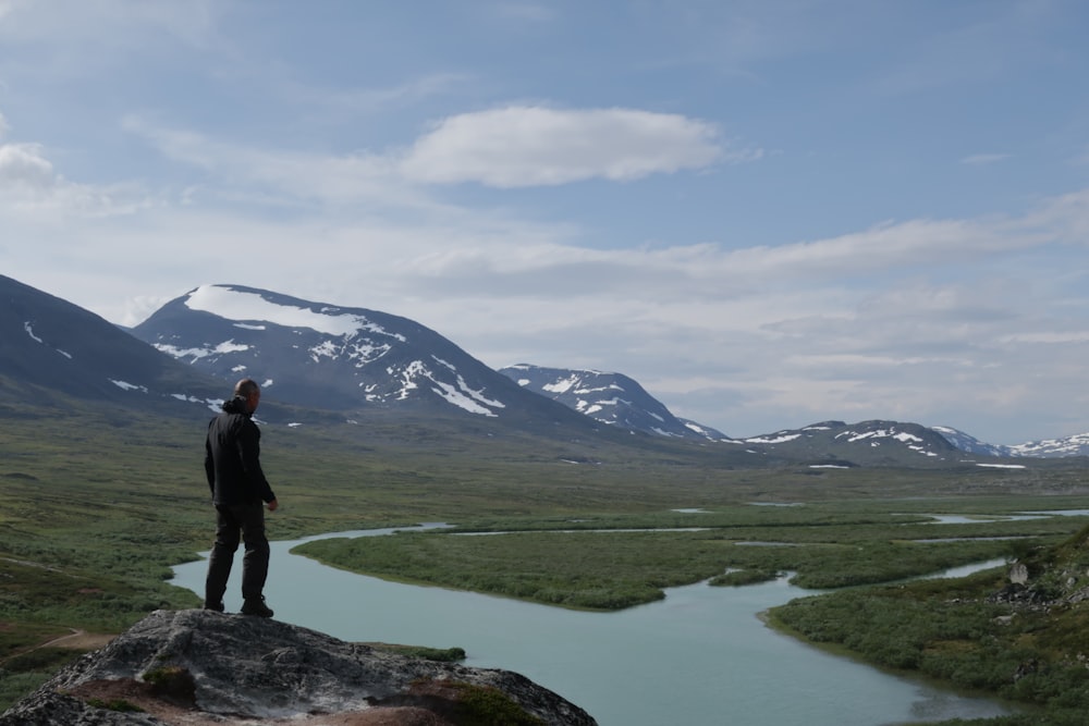 a man standing on top of a rock next to a river