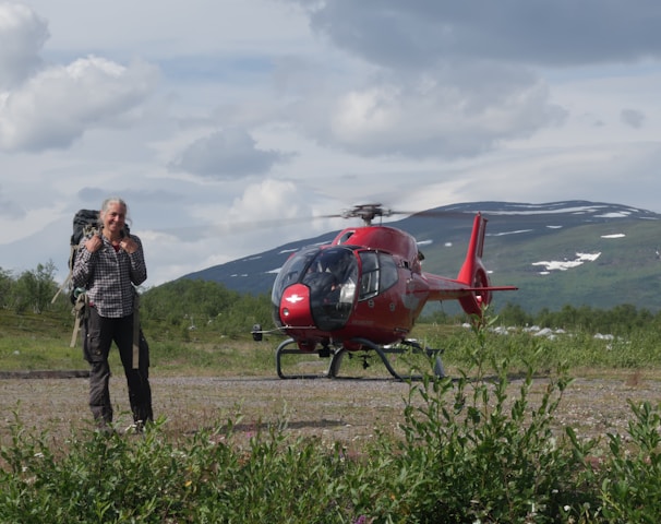 a man standing in front of a red helicopter
