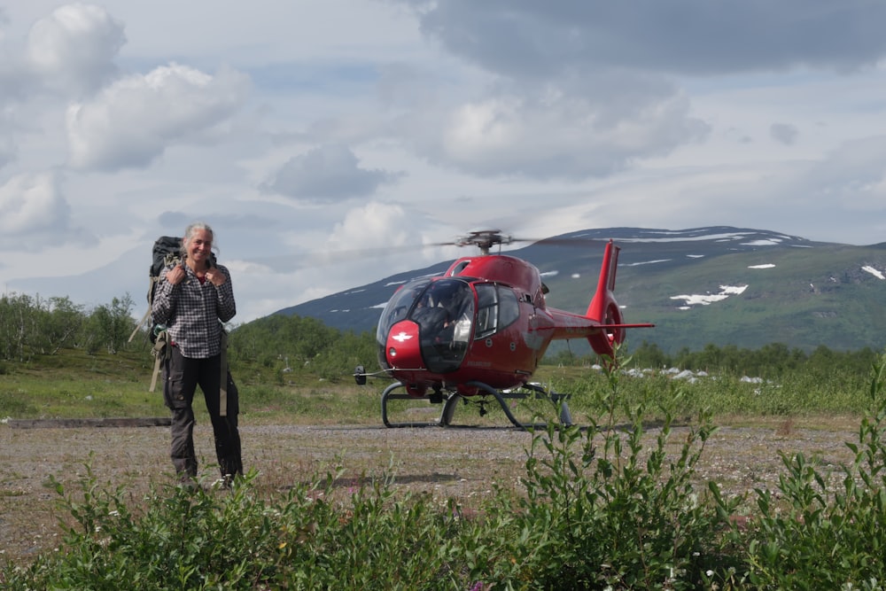 a man standing in front of a red helicopter