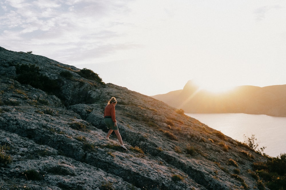 a person walking up a hill with a body of water in the background