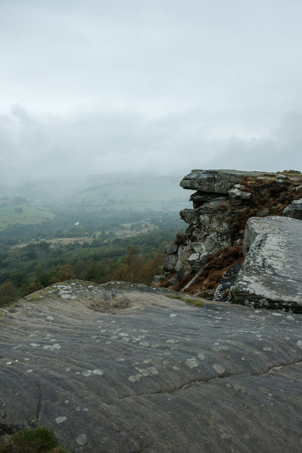 a rock outcropping with a view of a valley in the distance