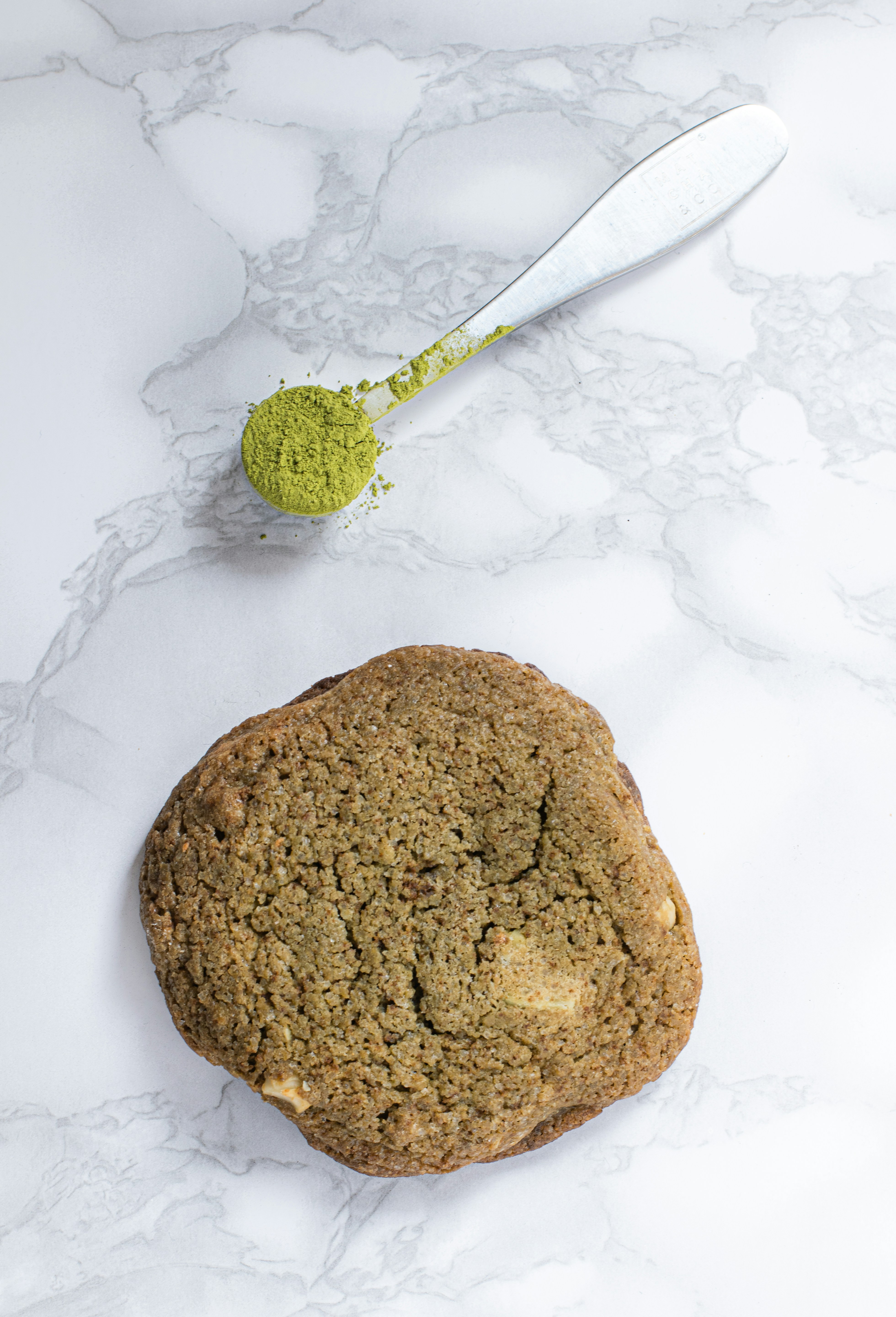 a cookie and a spoon on a marble surface