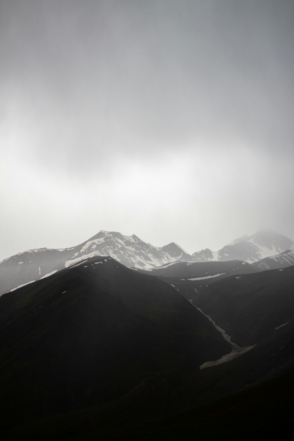 a mountain range covered in snow under a cloudy sky