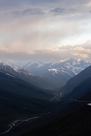 Snow-capped Himalayan peaks towering above a winding river, framed by frosted pine trees.