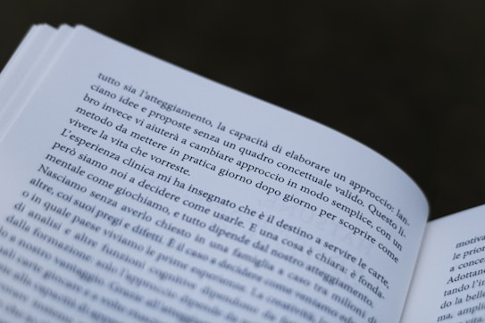 A close-up view of an open book with text in Italian. The pages are slightly curved, and the focus is on the text, making some words clear while others are slightly out of focus.