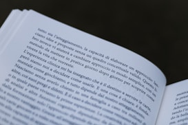 A close-up view of an open book with text in Italian. The pages are slightly curved, and the focus is on the text, making some words clear while others are slightly out of focus.