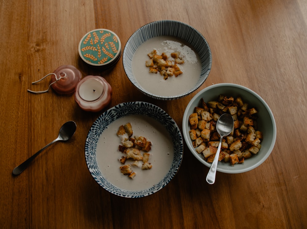 three bowls of food on a wooden table