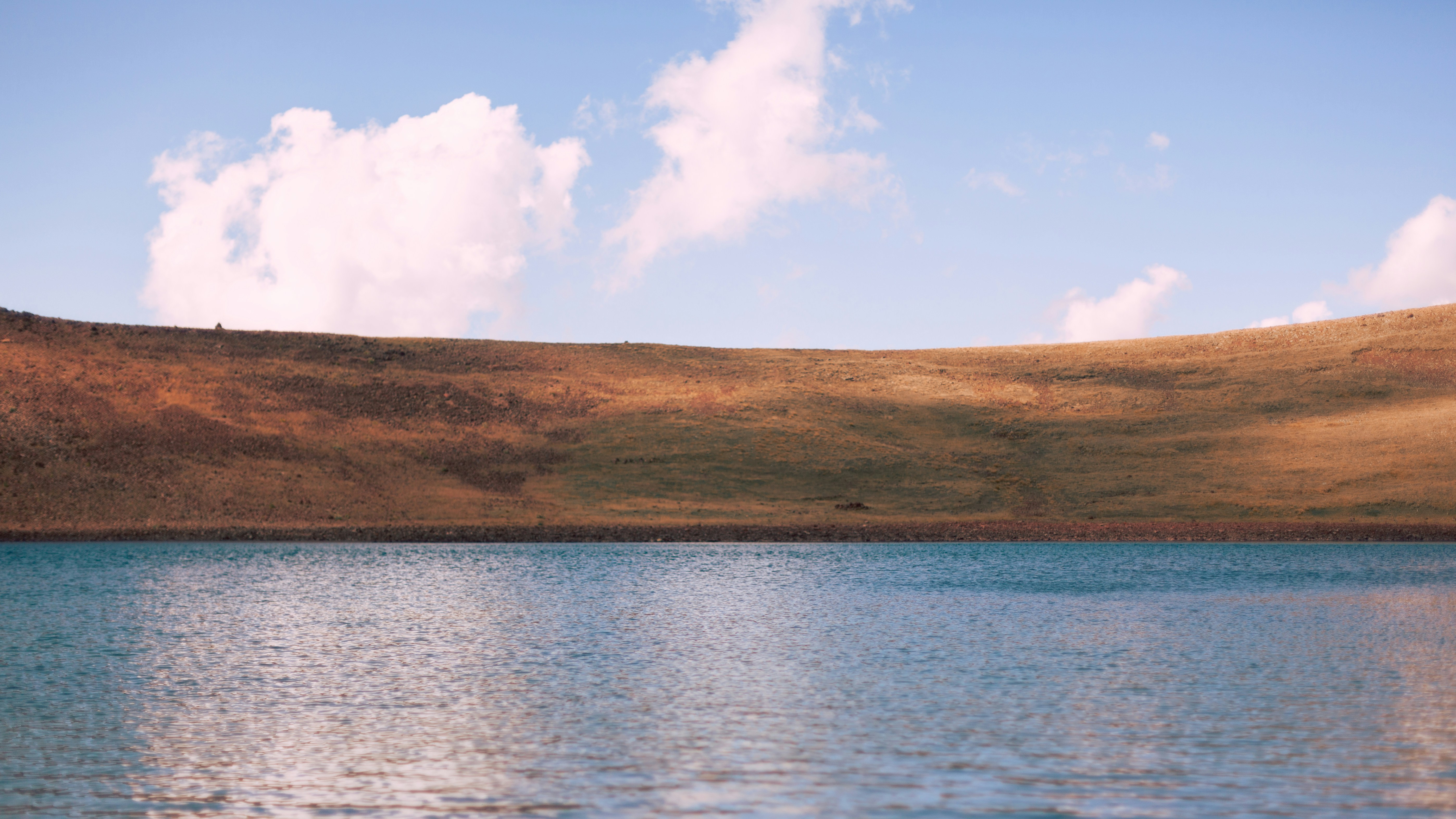 a body of water with a hill in the background