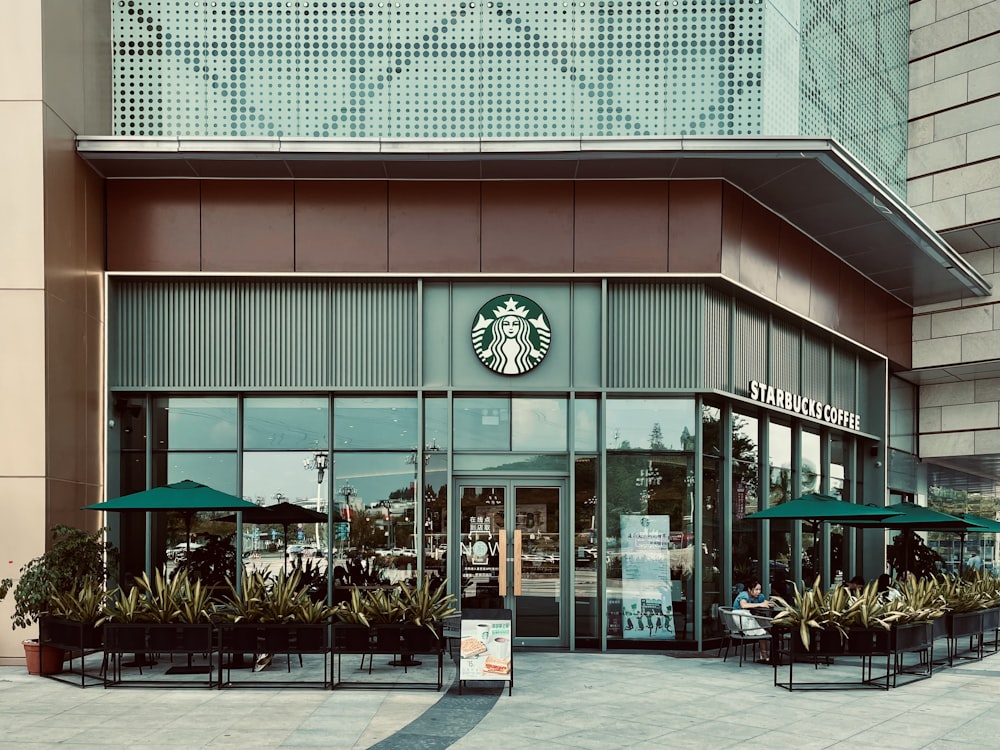 a starbucks coffee shop with green umbrellas and potted plants