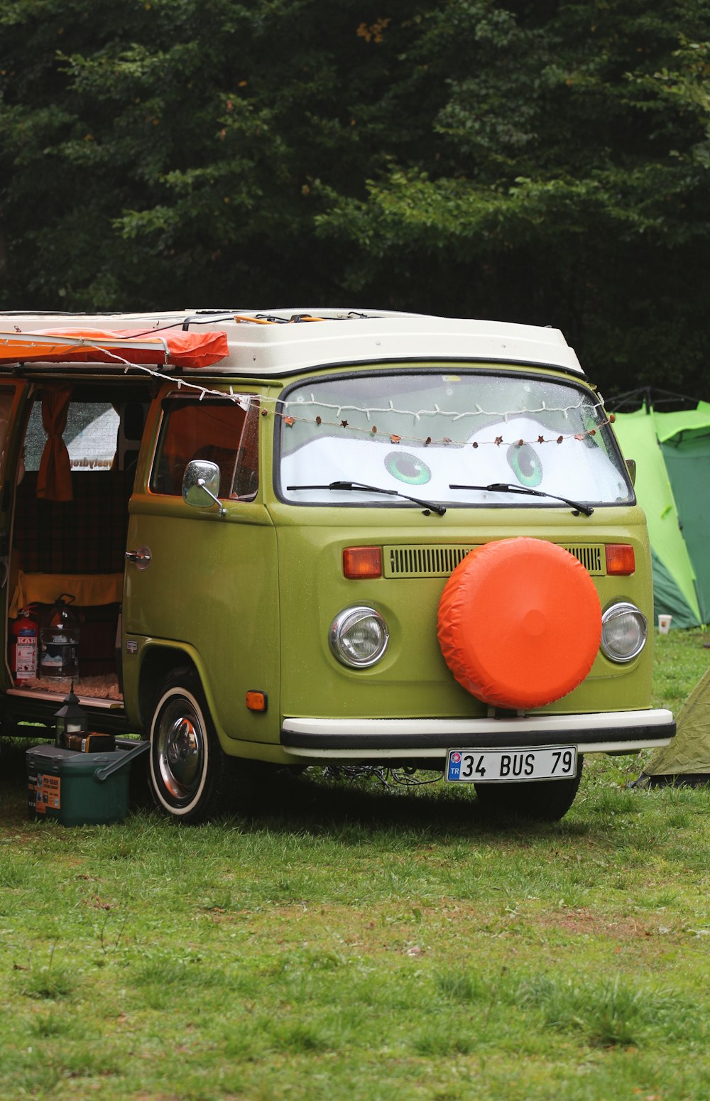 a green van parked in a field next to a tent
