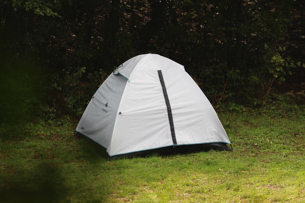 uma tenda branca sentada no topo de um campo verde exuberante