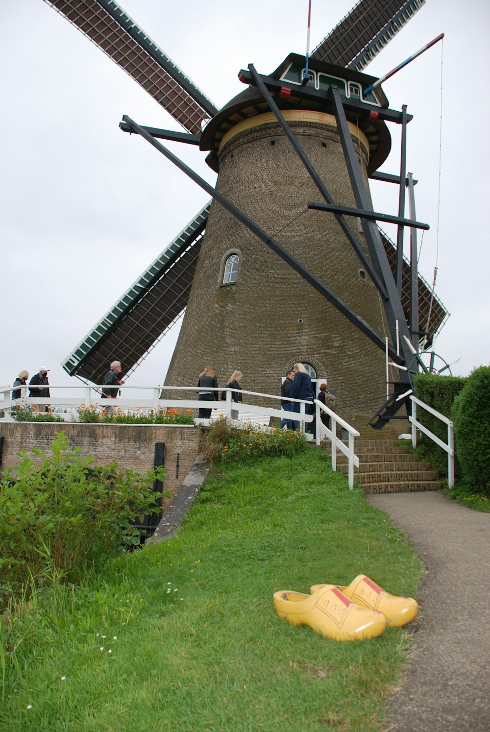 a yellow rubber shoe laying on the ground in front of a windmill