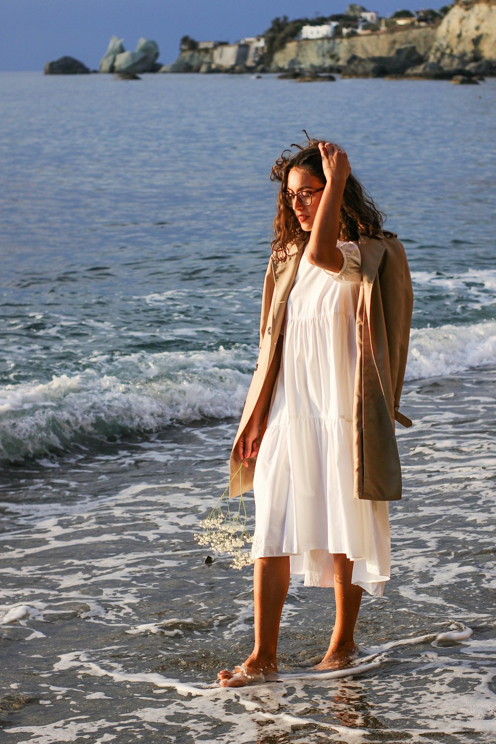 Una donna in un vestito bianco in piedi su una spiaggia foto – Spiaggia di  cava dell'isola Immagine gratuita su Unsplash