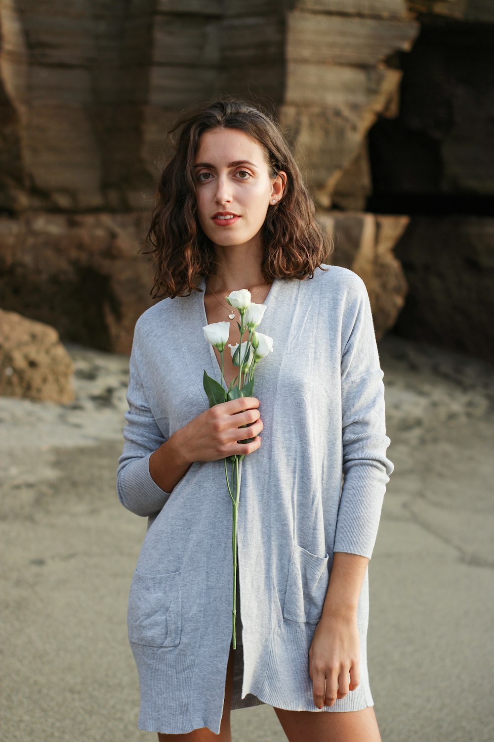 a woman standing on a beach holding a flower