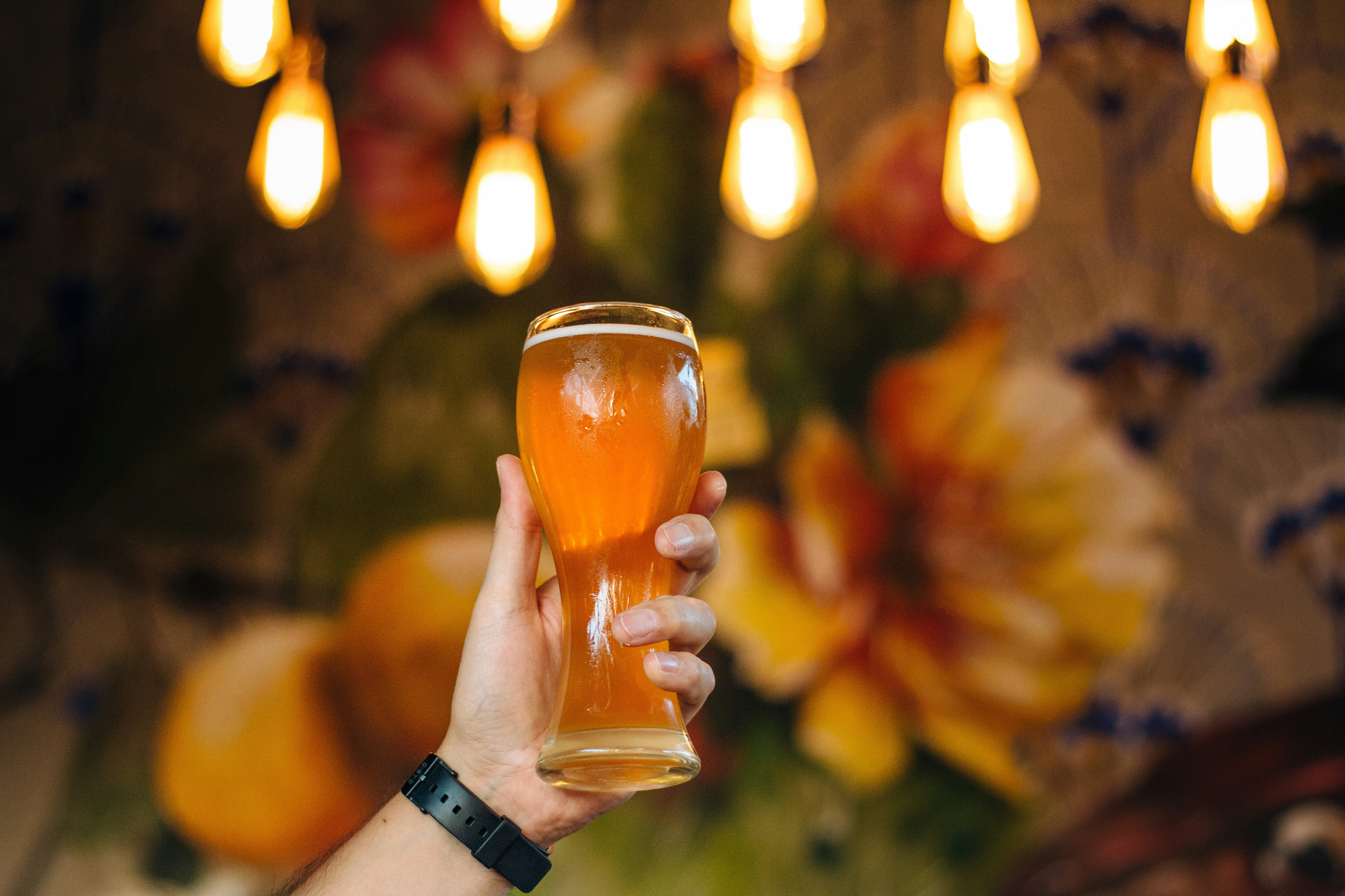 Hand holding a cider under warm lights