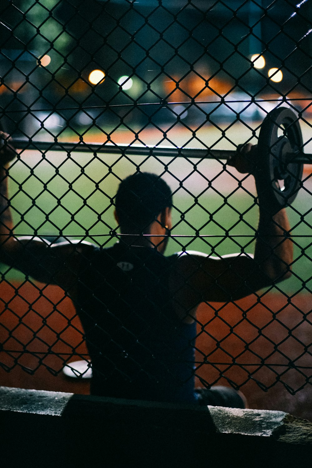 a man holding a baseball bat behind a fence