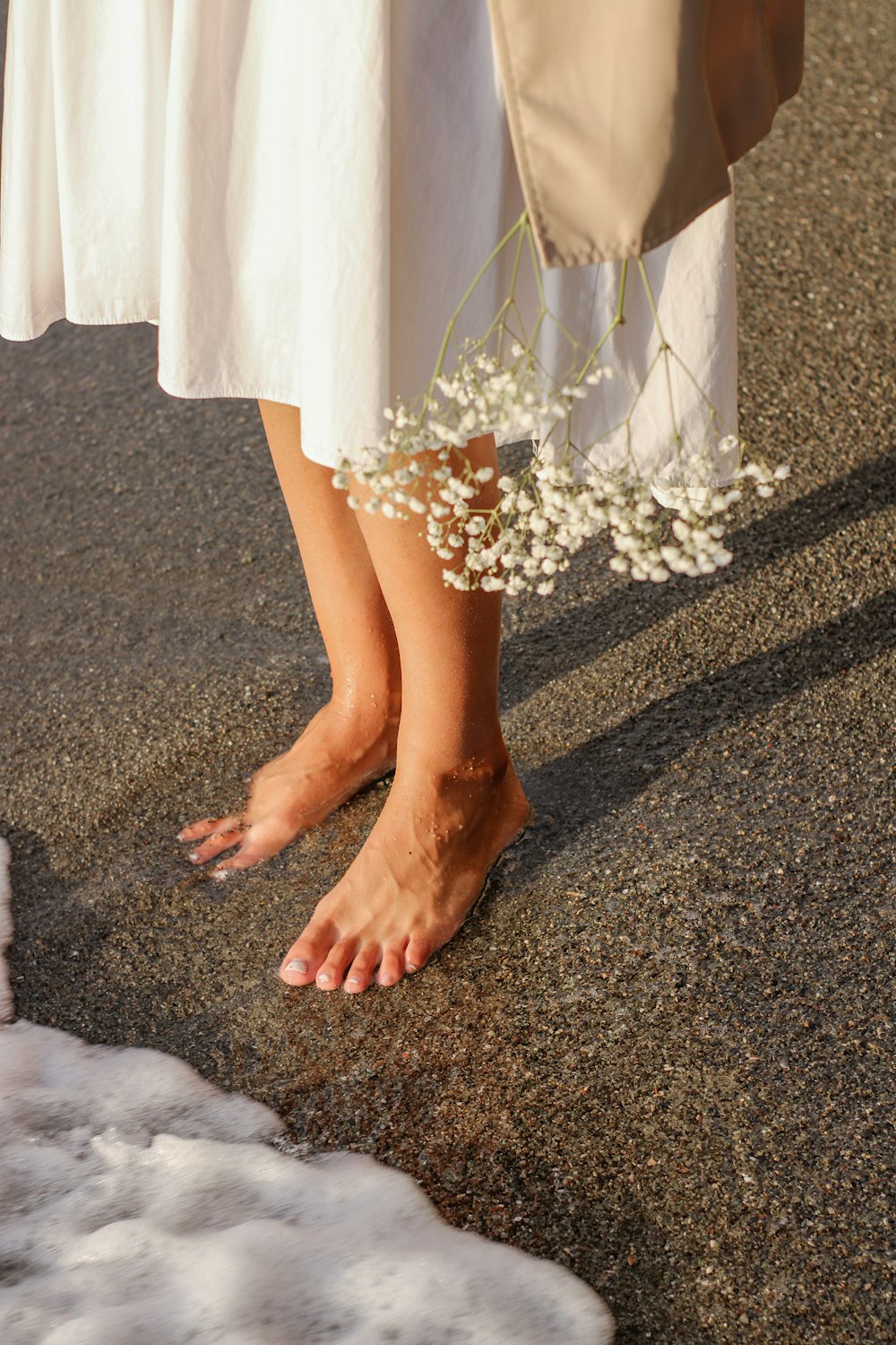 白い花の隣に立つ白いドレスを着た女性