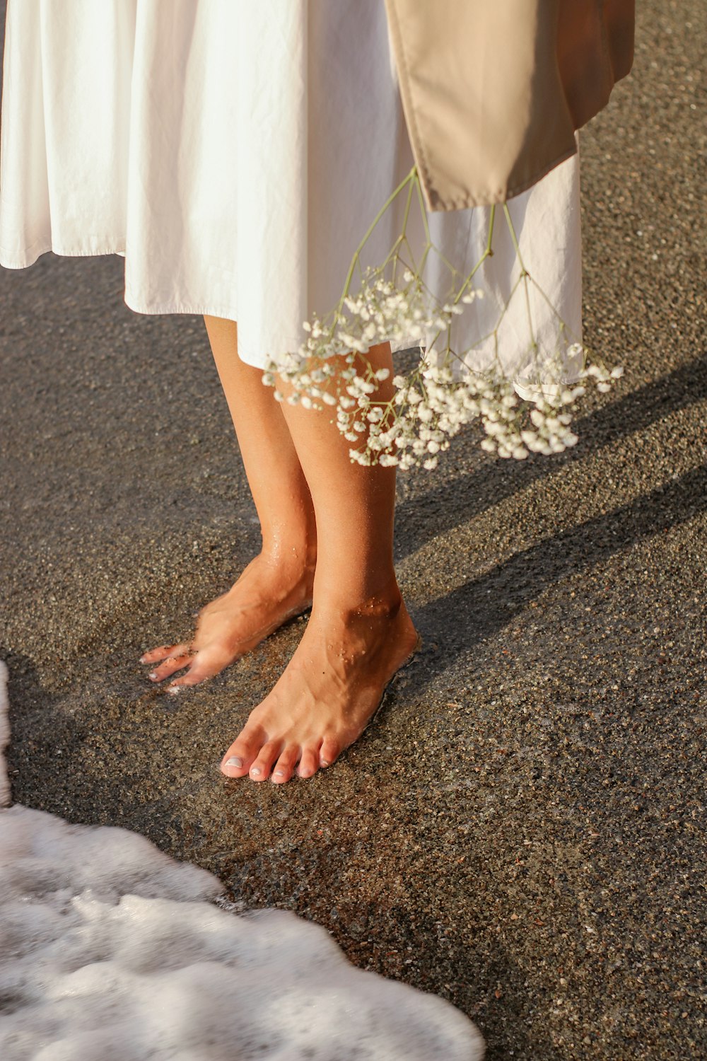 a woman in a white dress standing next to a white flower