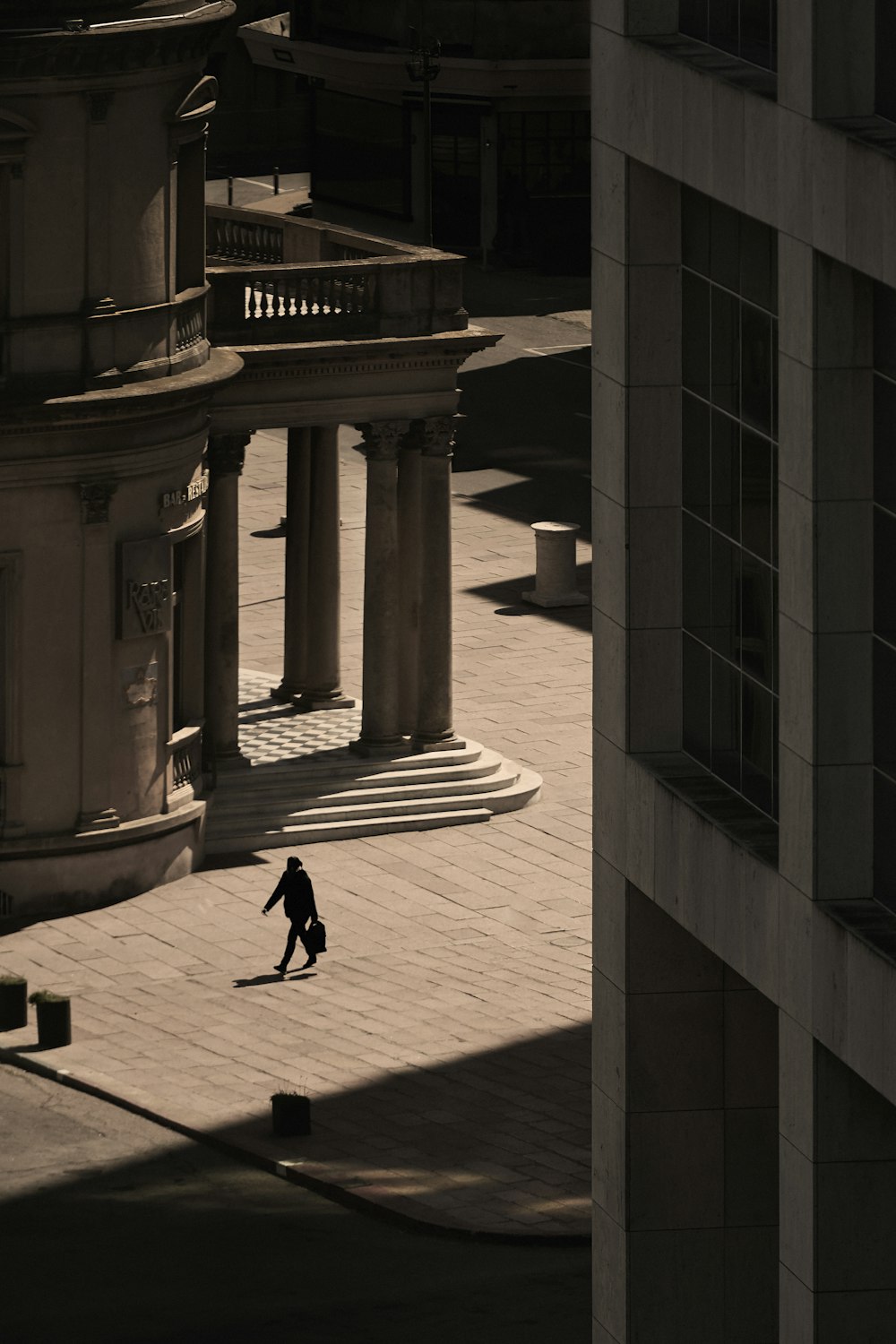 a person walking down a street next to a tall building