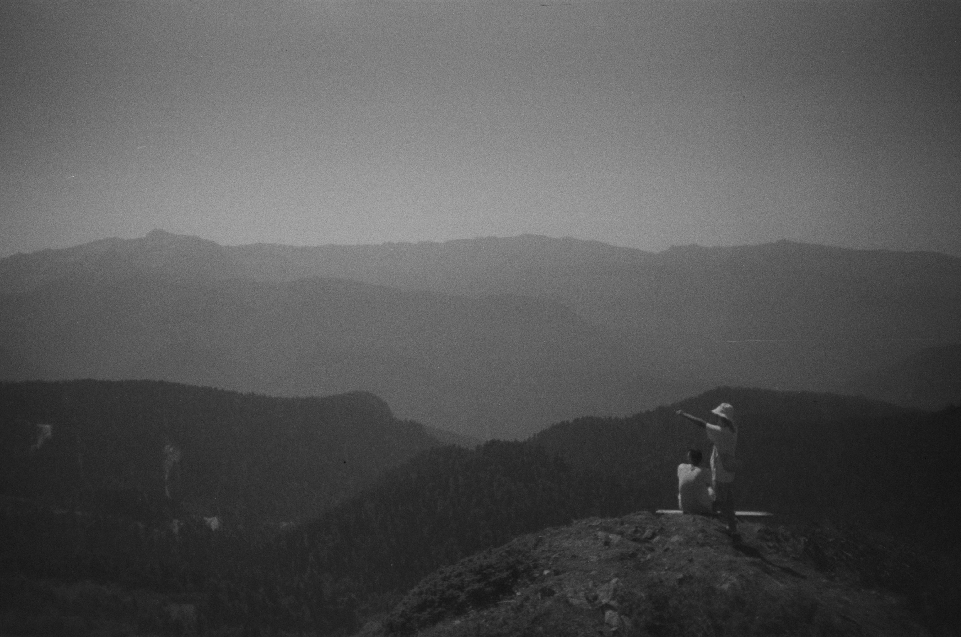 a man sitting on top of a mountain next to a dog